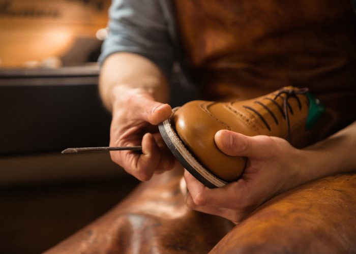 Cropped image of young shoemaker in workshop making shoes.